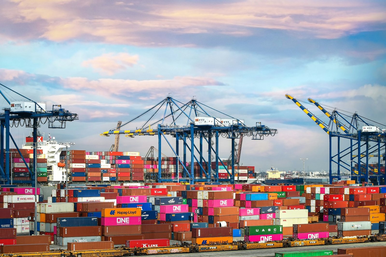 Shipping port with cranes loading containers at dusk